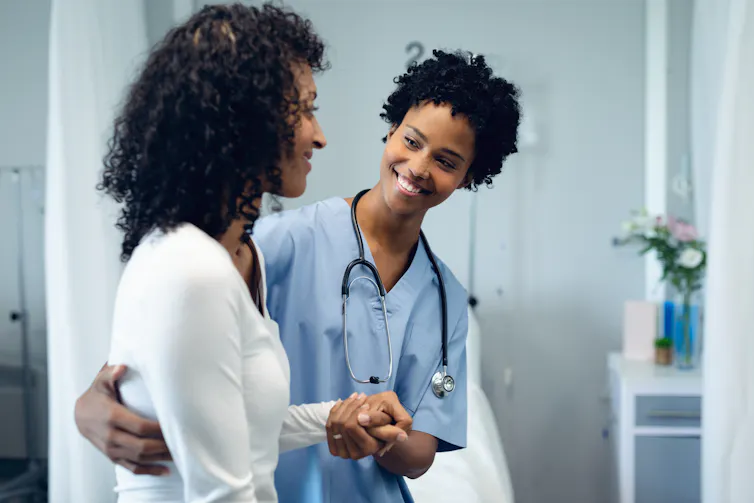A smiling nurse supports a patient.