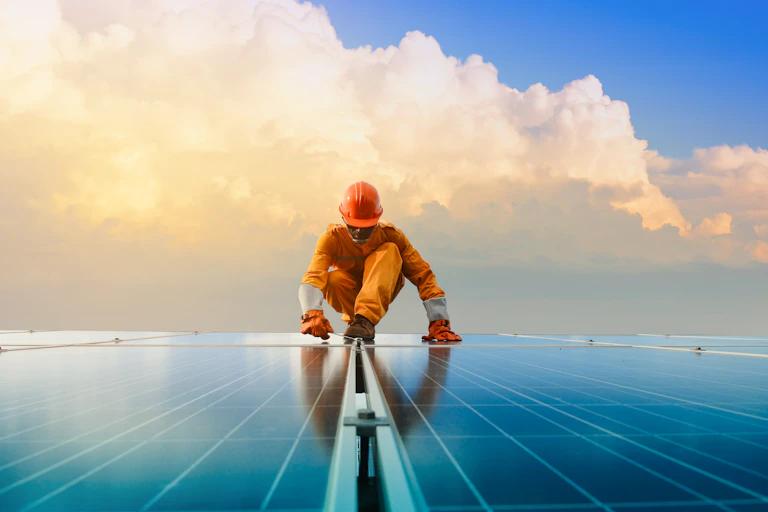 man in hard hat and overalls works on solar panels