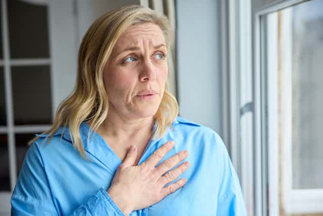 Woman stands with hand on heart area