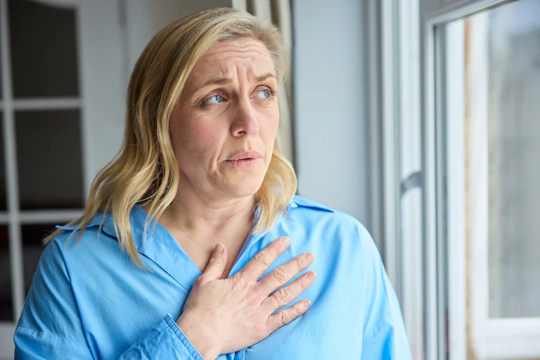 Woman stands with hand on heart area