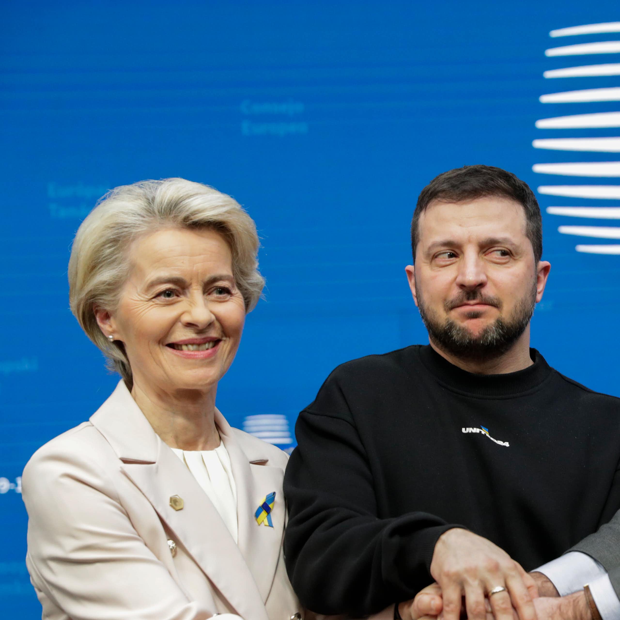 Ursula von der Leyen, Volodymyr Zelensky and Charles Michel clasping hands at a press conference