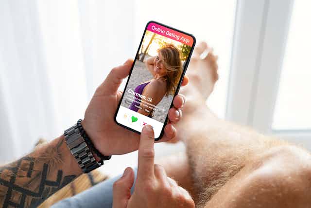 a man holds a phone with a photo of a blonde woman on it and the text Online Dating App
