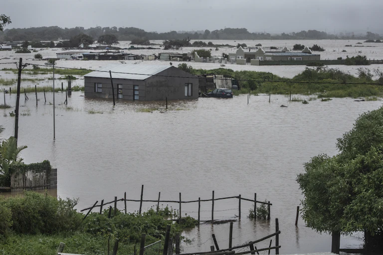 A very flooded suburb where only the tops of the houses and a few trees are seen sticking out of the water