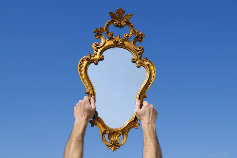 Two hands hold up a mirror.