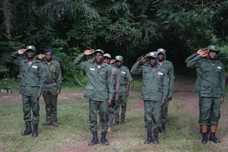 A group of men stand and salute.