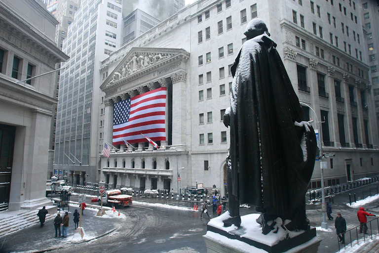 View of Wall Street and the New York Stock Exchange across a snowy street.