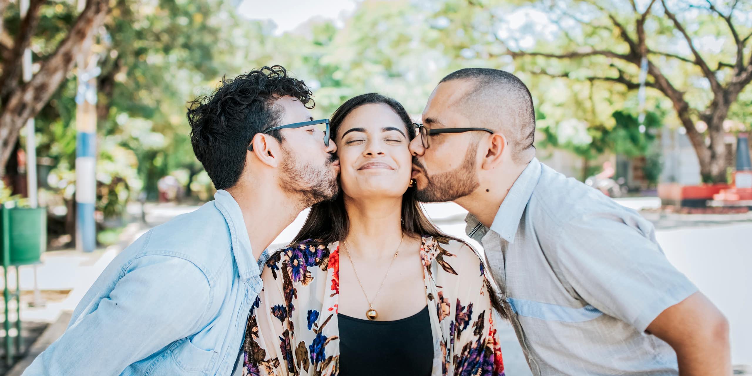 Two men kiss a woman on either cheek