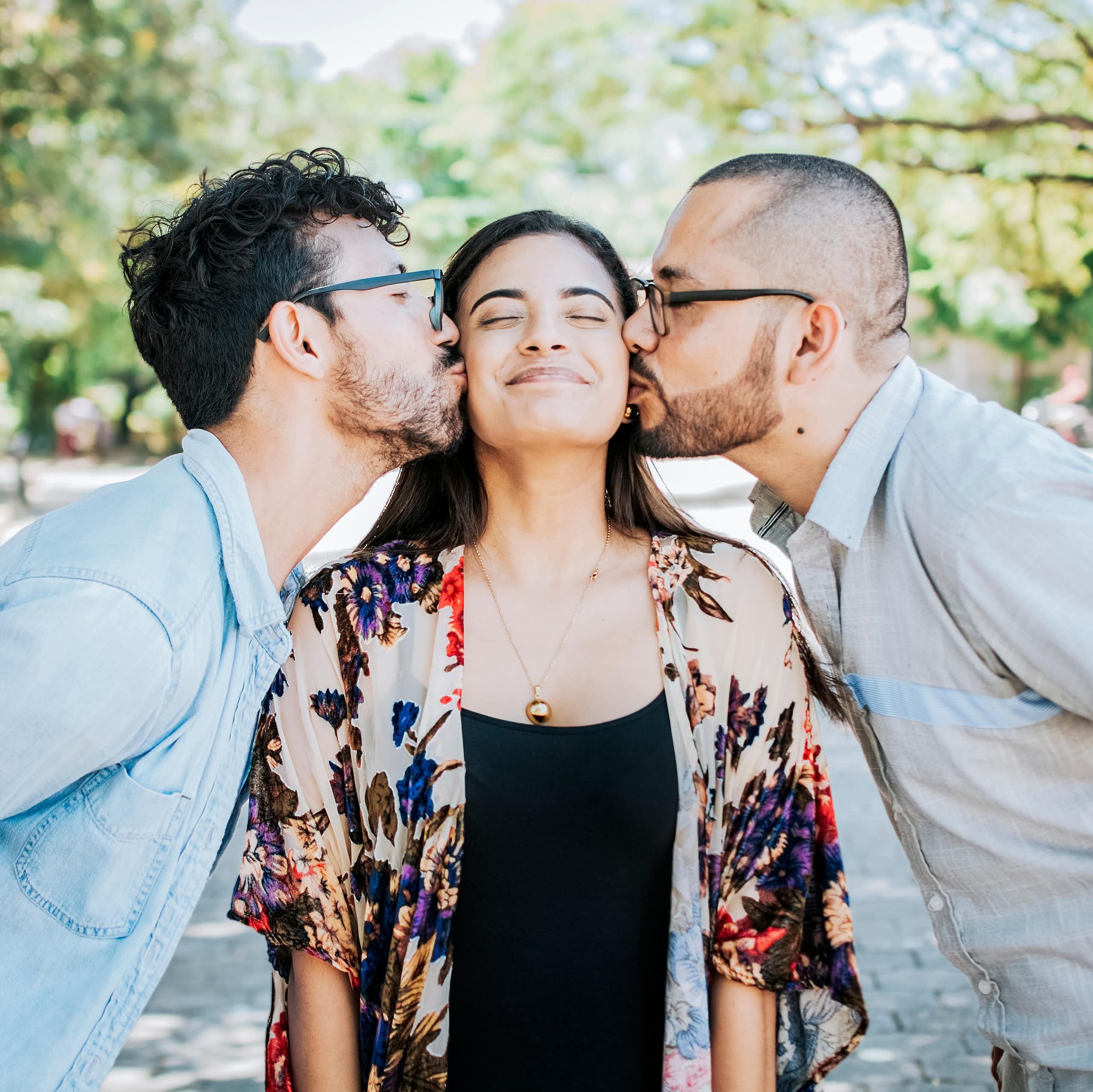 Two men kiss a woman on either cheek