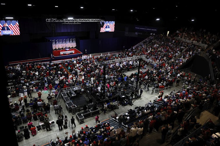 A crowd of people gather in an auditorium during a rally for Donald Trump.