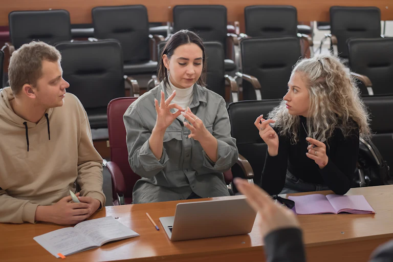 A woman using sign language to communicate with people sitting around a table