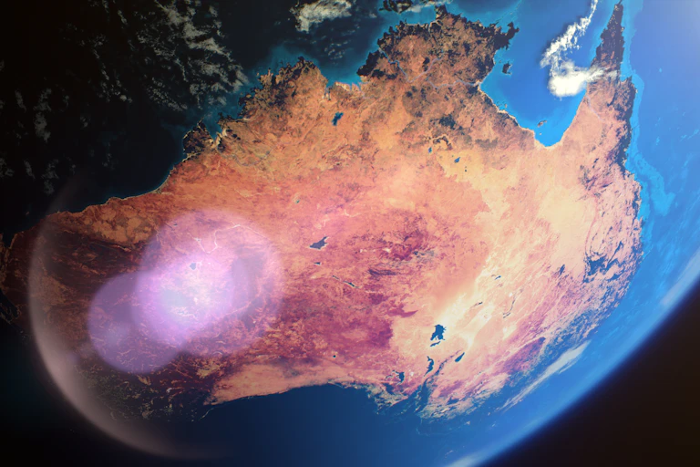 A view of Australia from space with a lens flare and surrounded by blue ocean.