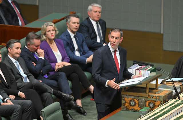Treasurer Jim Chalmers delivers his budget speech. Education Minister Jason Clare sits on the bench behind him, along with other ministers.