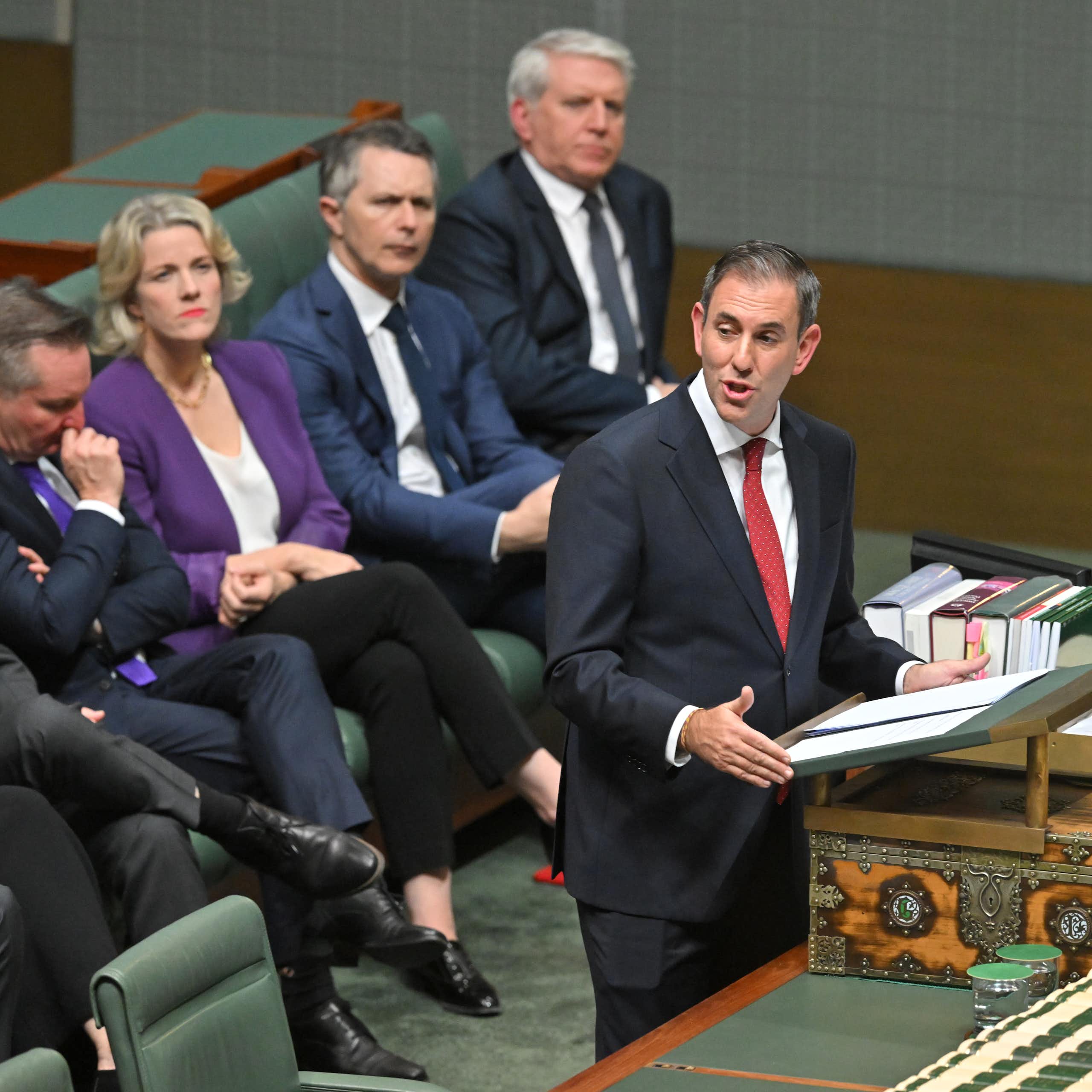 Treasurer Jim Chalmers delivers his budget speech. Education Minister Jason Clare sits on the bench behind him, along with other ministers.