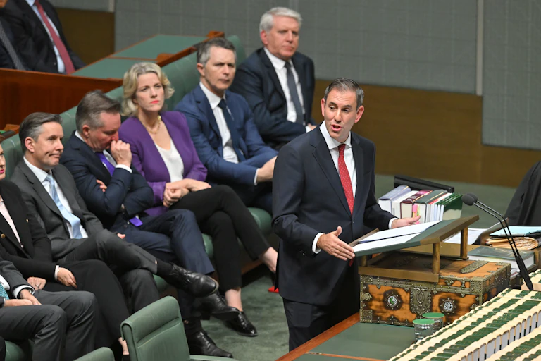 Treasurer Jim Chalmers delivers his budget speech. Education Minister Jason Clare sits on the bench behind him, along with other ministers.