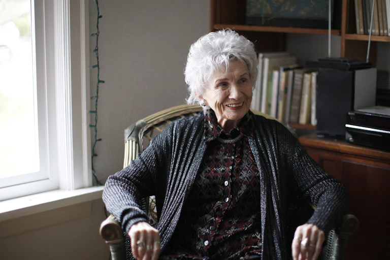 A woman sitting in a chair with natural light on her face from a window to the left.