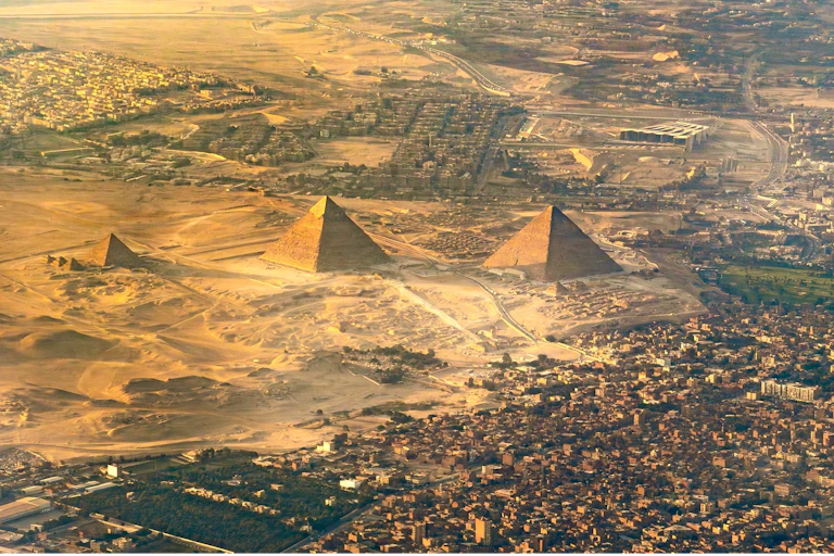 Aerial photo of pyramids with city nearby