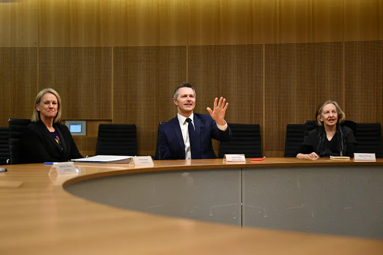 Education Minister Jason Clare and Professor Mary O'Kane sit at a conference table.
