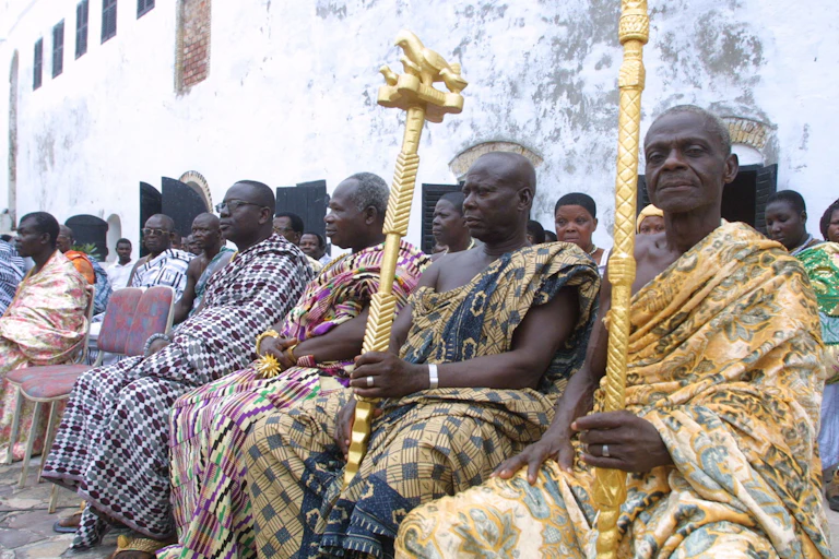 Men seated in a group holding staffs