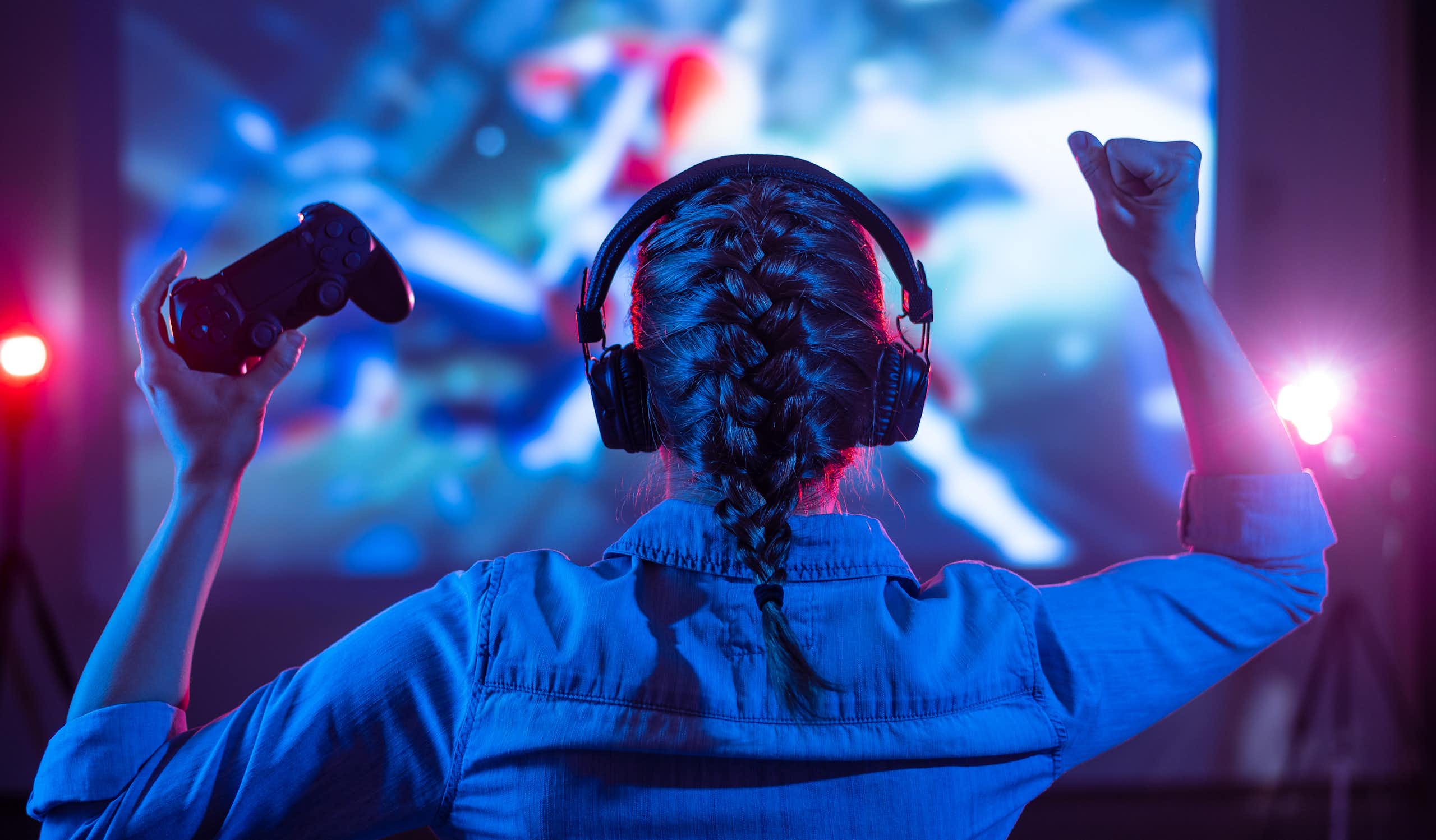 Girl in headphones plays a video game on the big TV screen