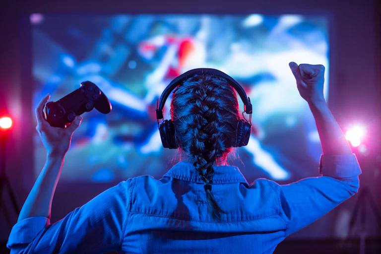 Girl in headphones plays a video game on the big TV screen