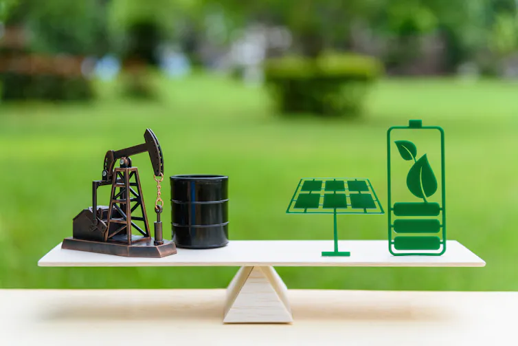 weighing scales concept with fossil fuels on left and green energy on right, blurry green garden background