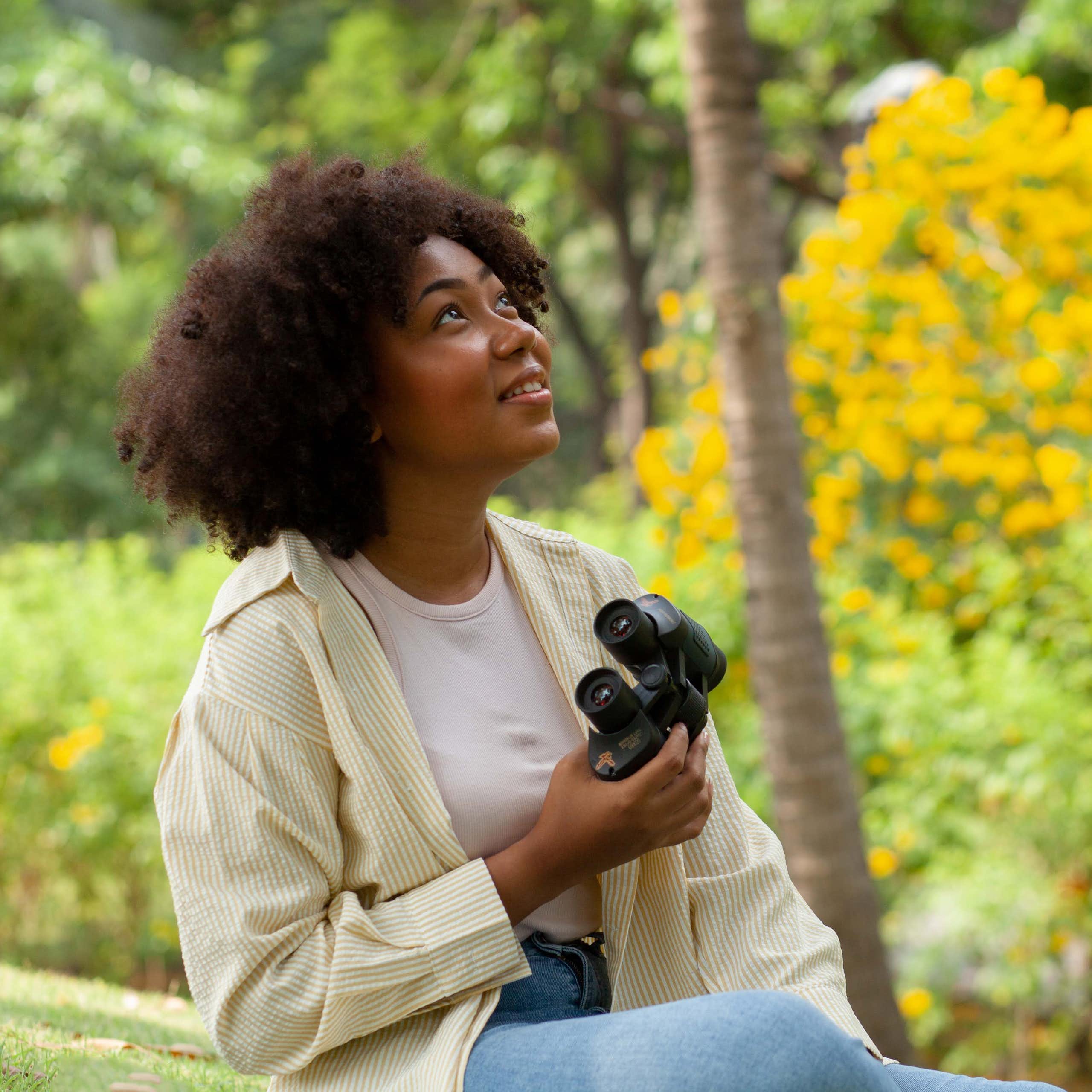 Woman holds binoculars and smiles while birdwatching