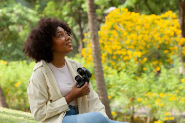 Woman holds binoculars and smiles while birdwatching
