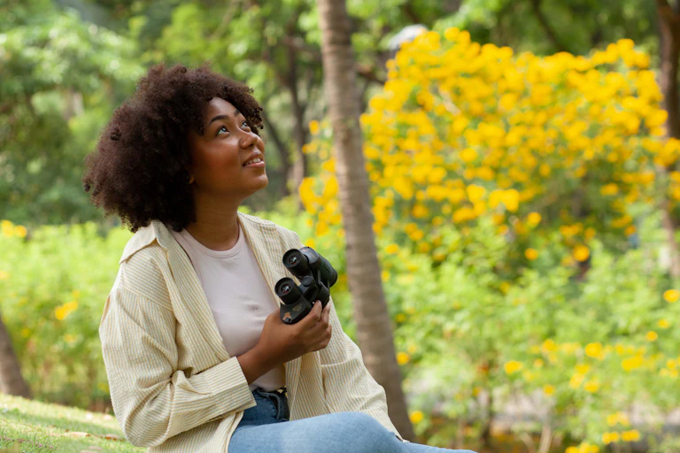Woman holds binoculars and smiles while birdwatching