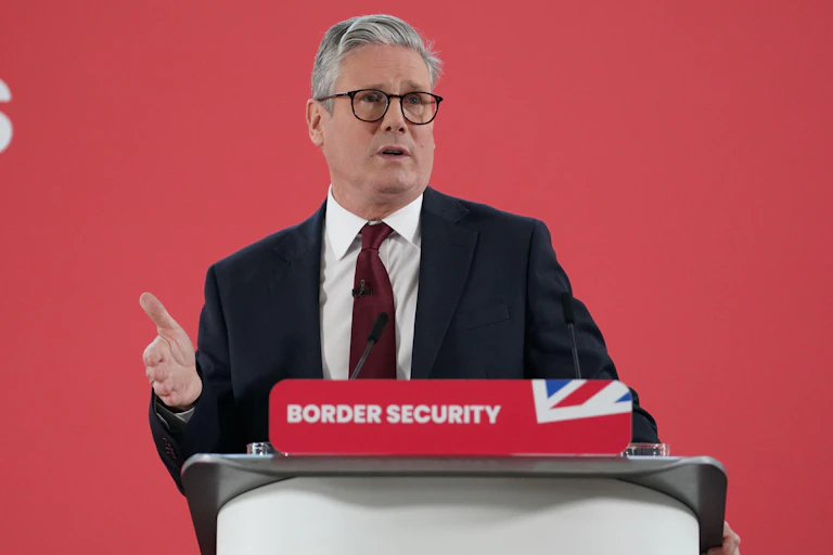 Keir Starmer speaking at a podium that has a red placard reading 'border security'