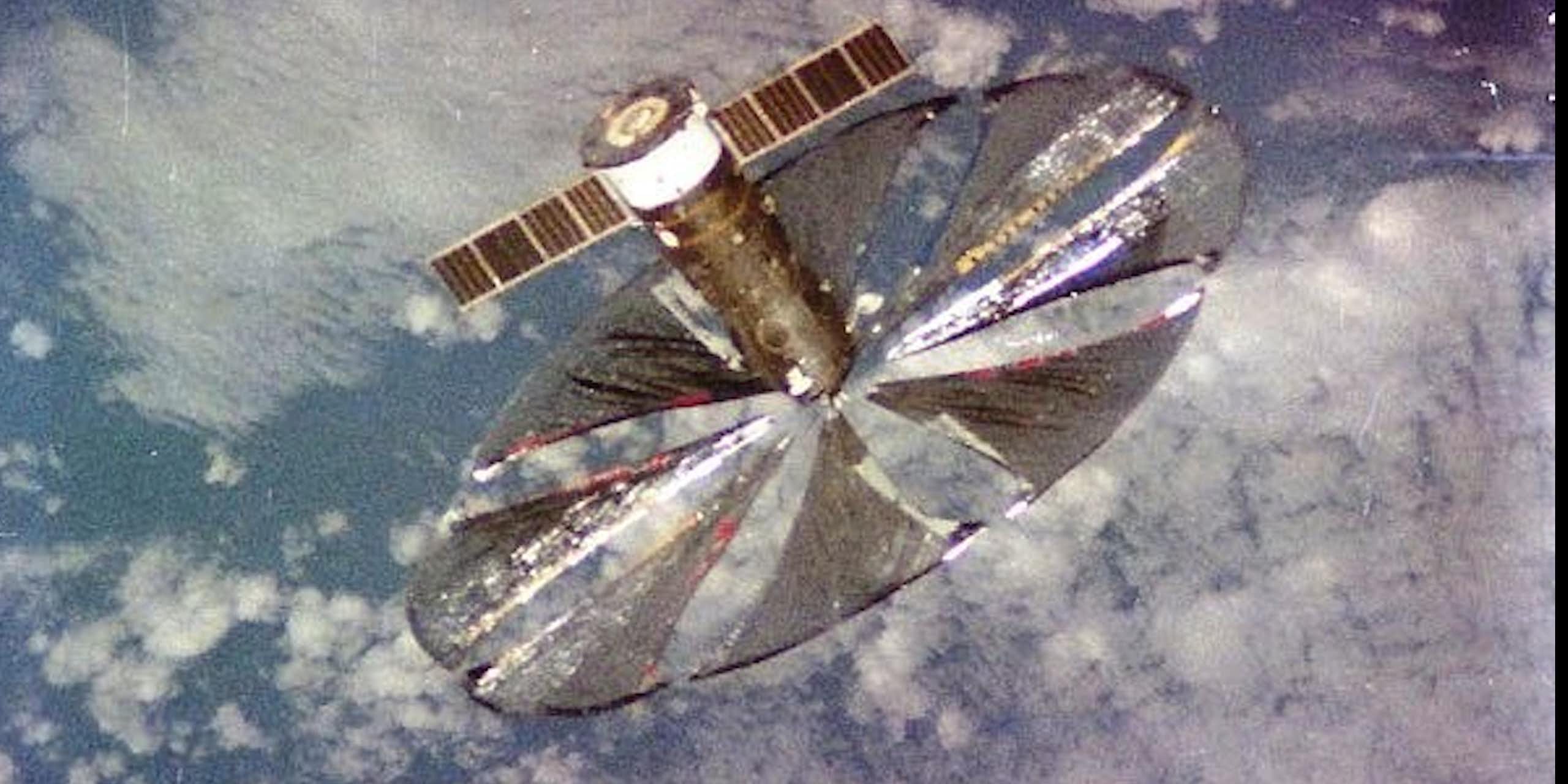 Vue de l’espace du réflecteur Znamia-2 : un satellite comportant de grandes voiles formant un disque argenté pour refléter la lumière du soleil.