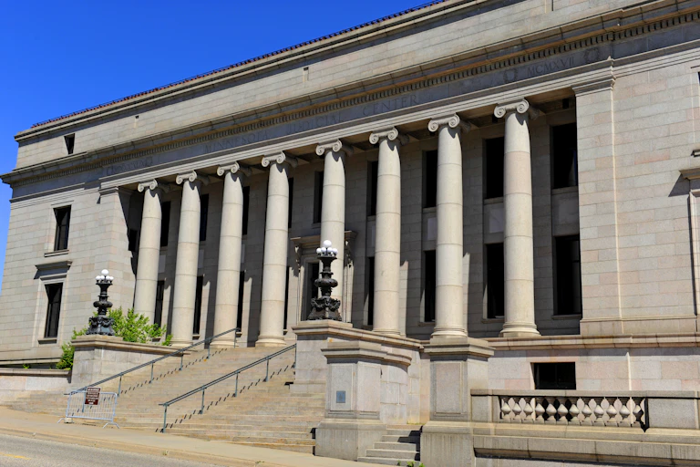 A large granite building with columns and a big staircase in front.