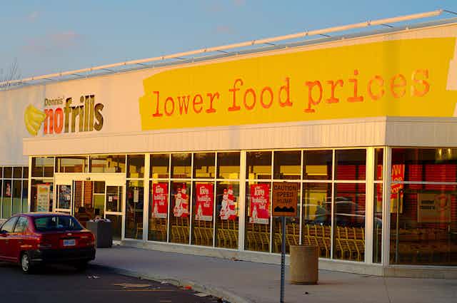 Storefront of a Canadian grocer, with "lower food prices" painted largely on the facade