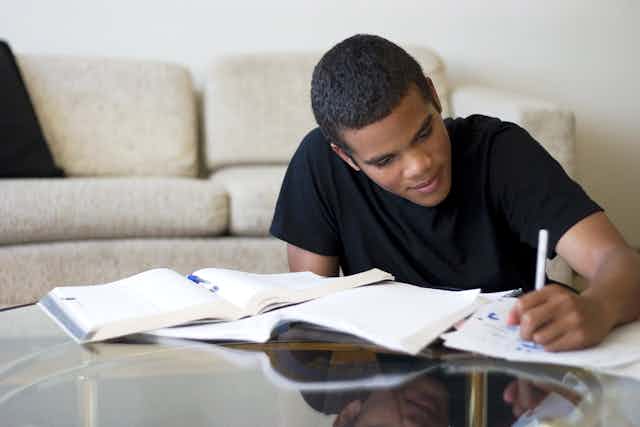 Teen boy studying at living room table