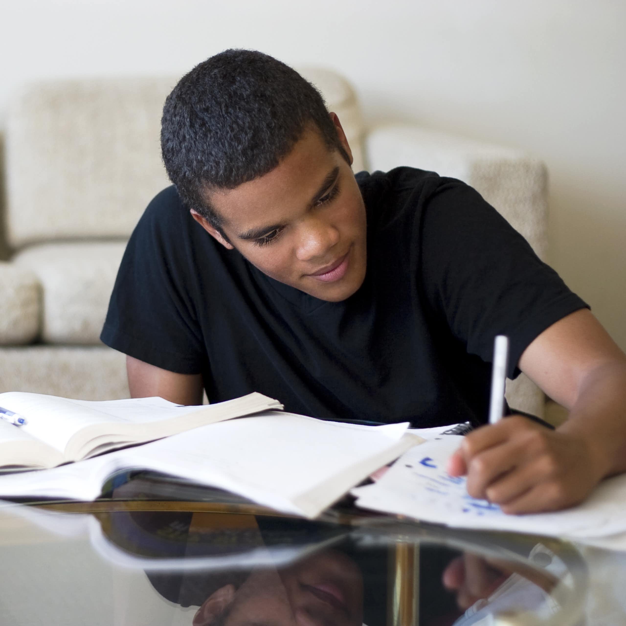 Teen boy studying at living room table