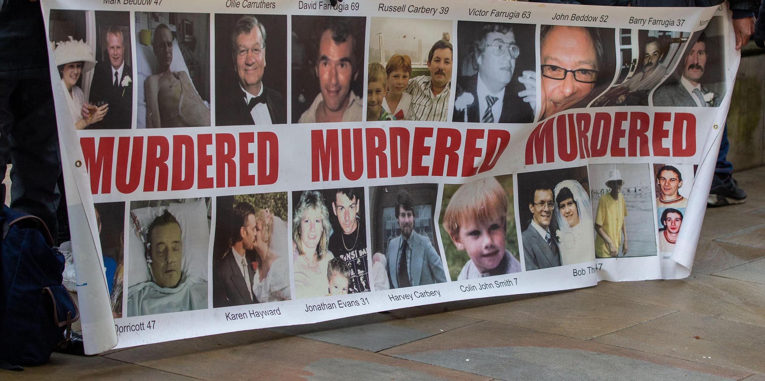 People holding up a banner showing the faces of their family members who have died