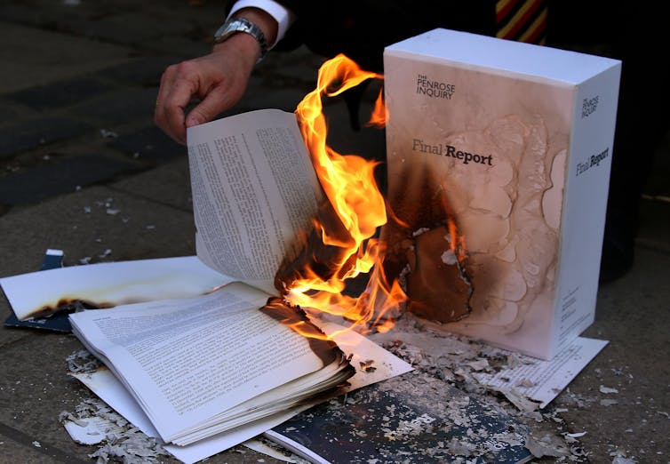 A large report with its pages being set light to.