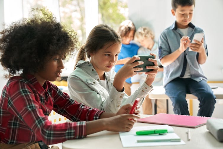 A group of children in a classroom using smartphones