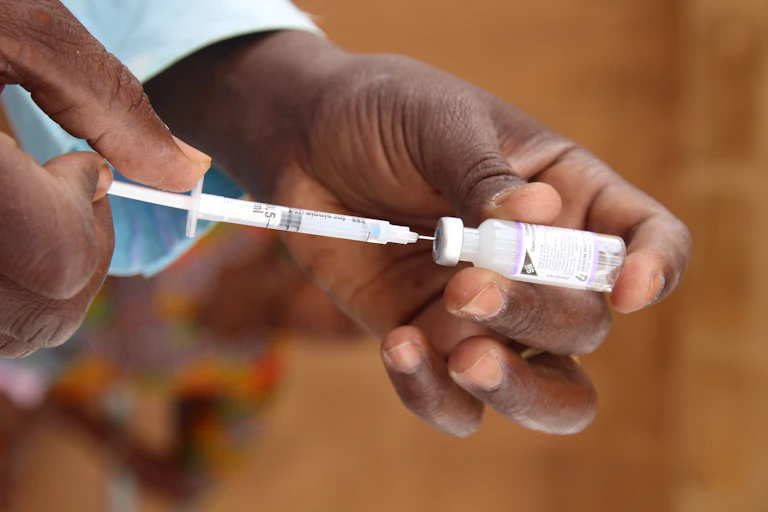Hands holding a syringe and a small bottle