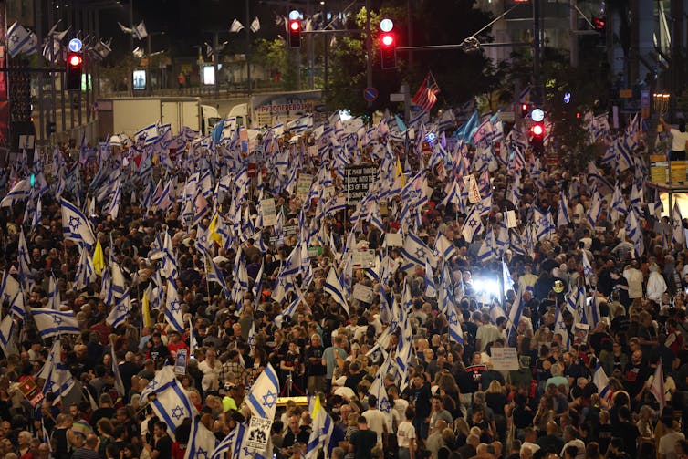 A large crowd of people holding Israel flags.