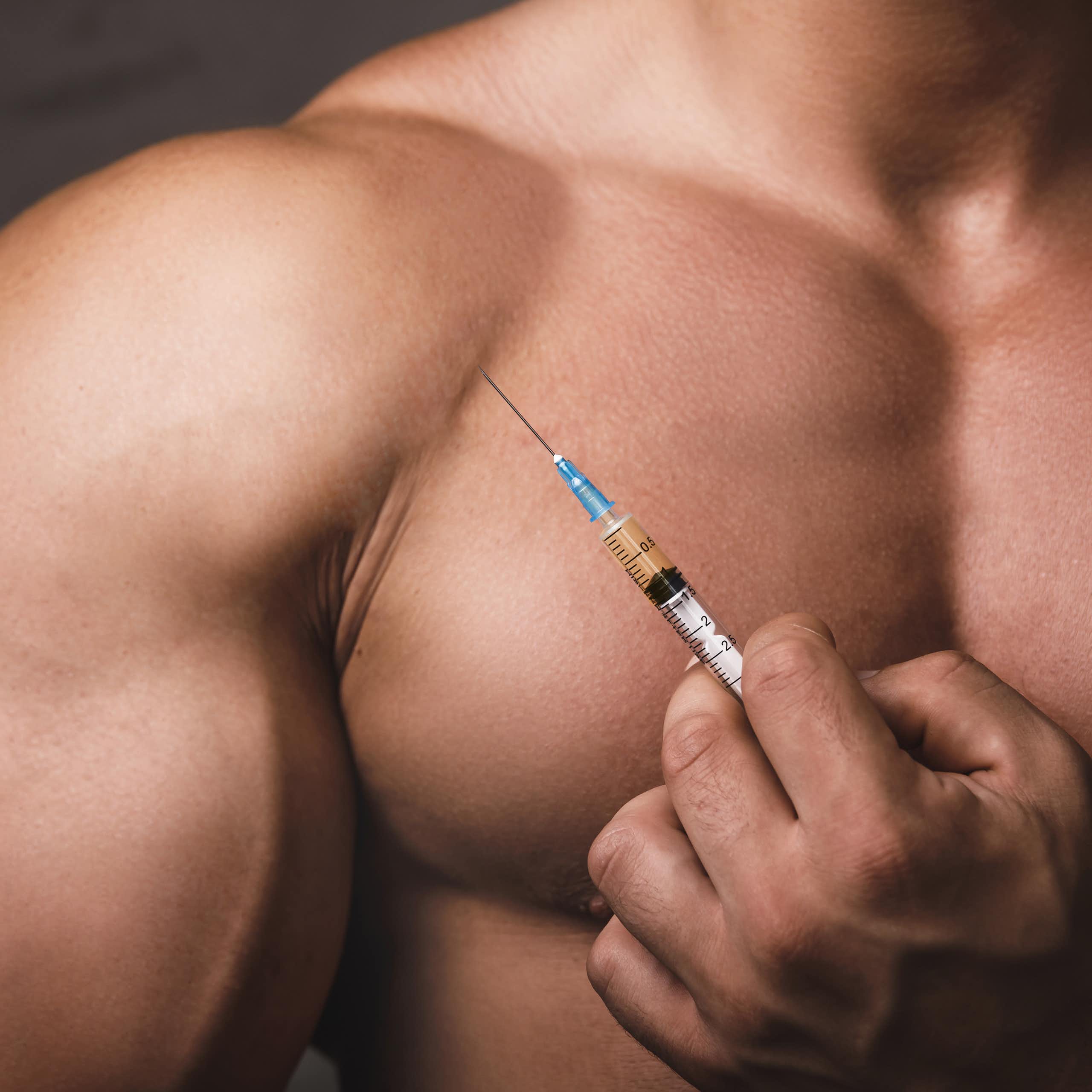 A muscular man holds a medical syringe.