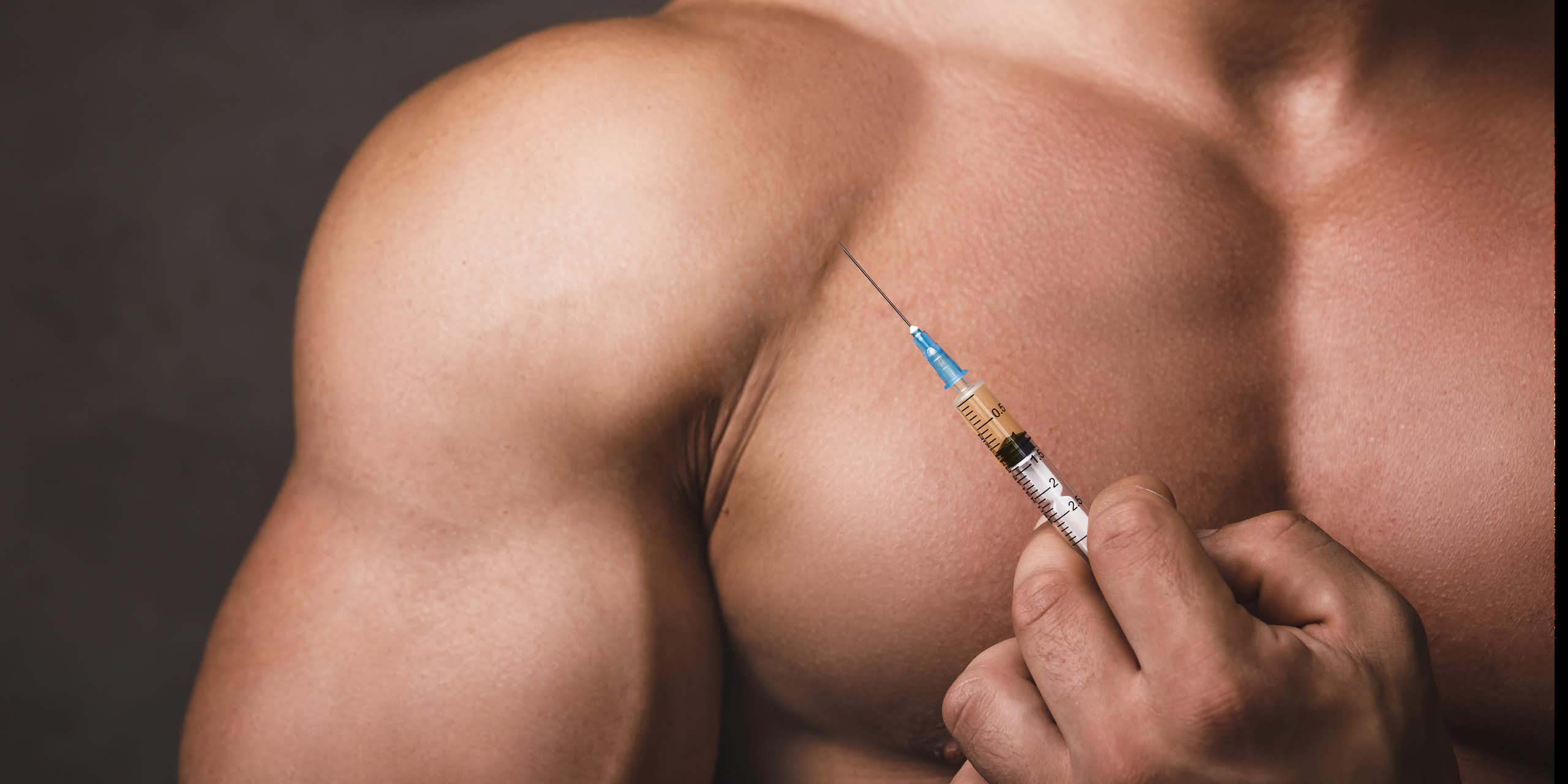 A muscular man holds a medical syringe.