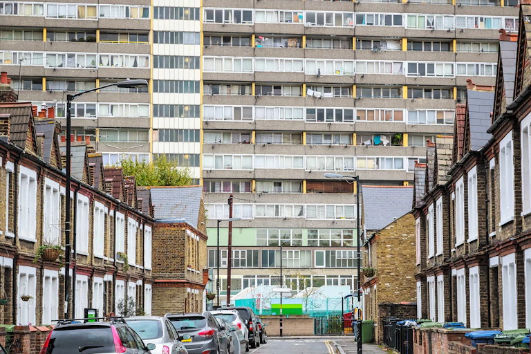 A street of terraced houses with a large council estate visible in the background