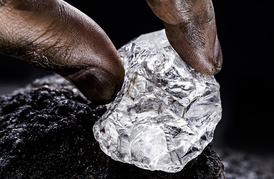 Fingers holding a lump of a shiny substance
