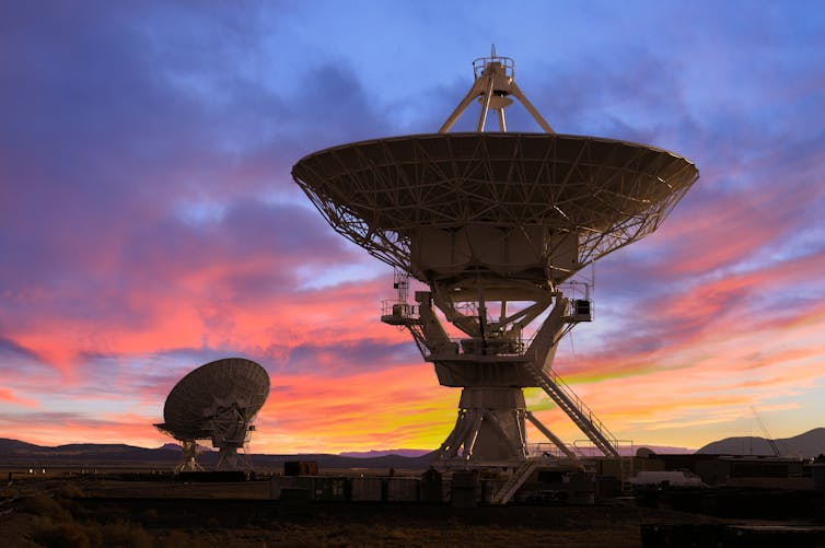 Two large radio telescope dishes at dusk.