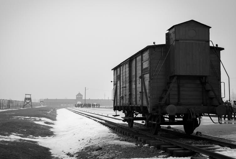 Black and white image of a train carriage outside Auschwitz