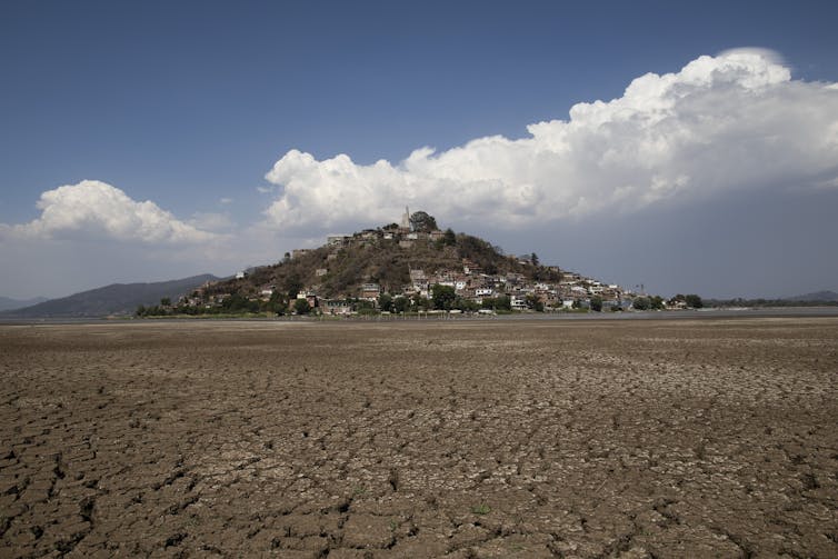 A small settlement on a hill rises out of a dry lake bed.