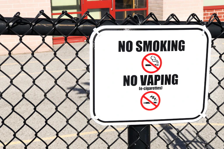 A no smoking, no vaping sign seen on a fence.
