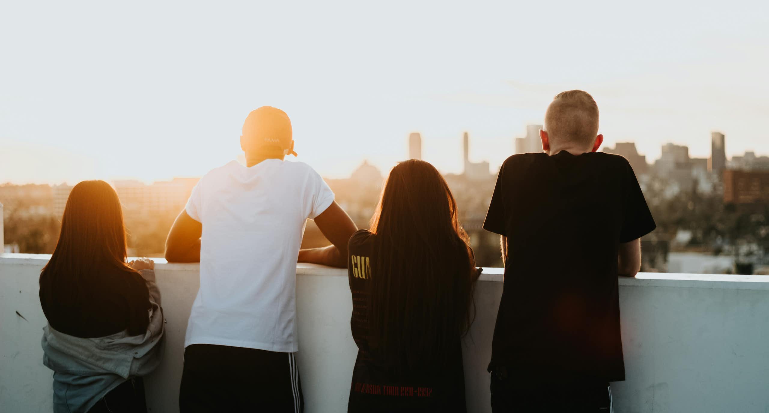 Young people seen looking over a balcony at a sunset.
