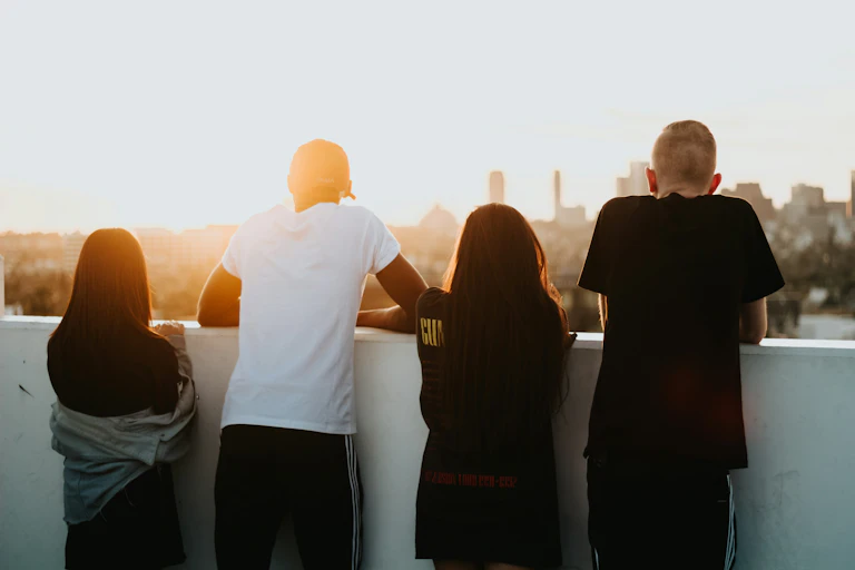 Young people seen looking over a balcony at a sunset.