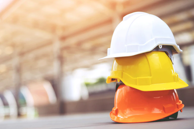 Three hard hats stacked on top of each other on the ground